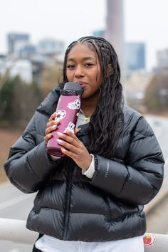 Woman with braided hair drinking from a water bottle outdoors