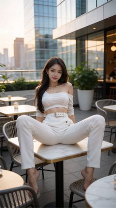 Woman in a white crop top and pants posing on a table at an outdoor cafe