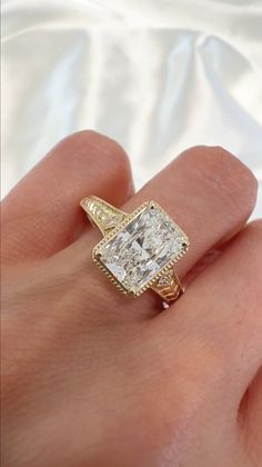 Hand wearing a yellow gold engagement ring with a radiant cut diamond