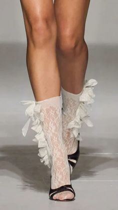 Person wearing white lace socks with ruffles and black open-toe heels