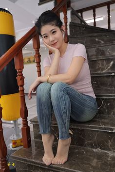 Woman in a pink t-shirt and blue jeans sitting on marble stairs