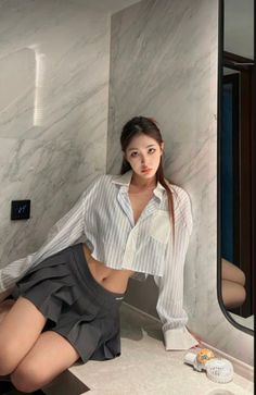 Woman in a cropped striped shirt and pleated skirt posing indoors