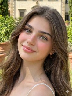 Woman with long brown hair and green eyes smiling outdoors