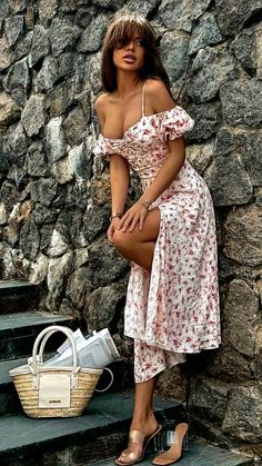 Woman in a floral dress with a high slit and exposed cleavage posing outdoors