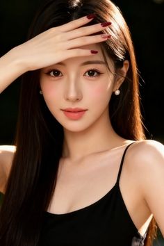Woman with long dark hair wearing a black camisole and pearl earrings