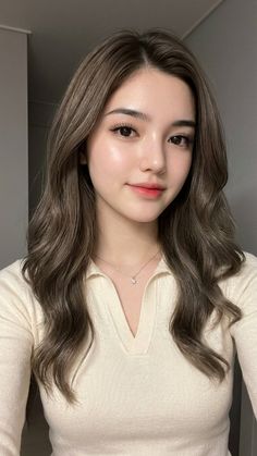 Woman with long wavy hair wearing a collared shirt and necklace
