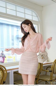 Woman in a pink blouse and mini skirt indoors by a window