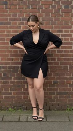 Woman in a black blazer dress with a high slit and gold hoop earrings