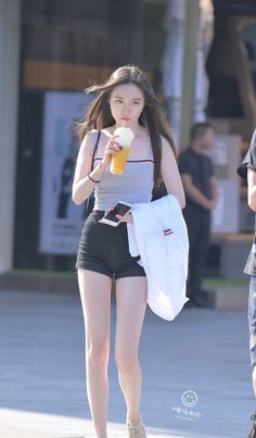 Woman with long hair in a tank top and denim shorts walking outdoors