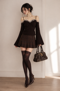 Woman in an off-shoulder top, pleated skirt, and thigh-high stockings holding a bag