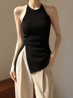 Woman in a black halter top and beige pants with soft indoor lighting