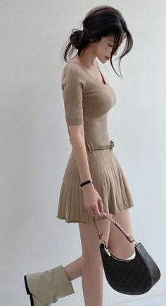 Woman in a fitted knitted dress with a handbag and boots