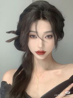 Woman with dark long hair and red lipstick wearing an off-shoulder top and necklace