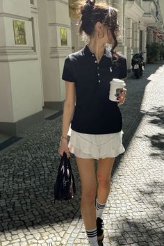 Woman in a black polo shirt and white mini skirt walking on a cobblestone street