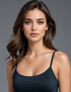 Woman with long dark hair wearing a spaghetti strap top against a gray background