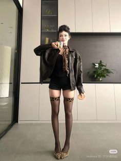 Woman in a leather jacket and leopard print stockings holding a glass