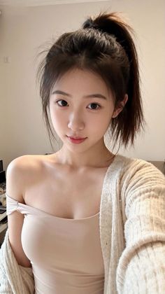 Woman with a ponytail wearing an off-shoulder top and cardigan indoors