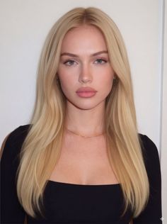 Woman with long blonde hair and blue eyes wearing a black top and gold necklace
