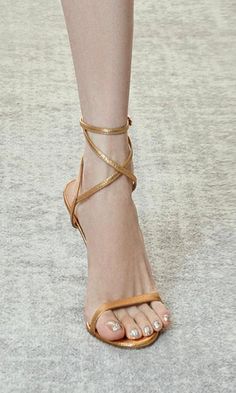 Close up of a foot wearing gold strappy sandals with silver glitter pedicure