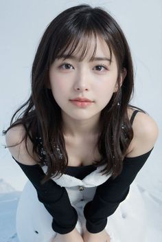Woman with long black hair and bangs in a black top and white dress in snow