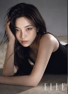Woman with long dark hair and freckles lying down in a black top