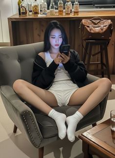 Woman in a tank top and shorts sitting in a chair, looking at her phone