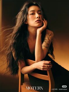 Woman with long dark hair and a black dress posing on a chair