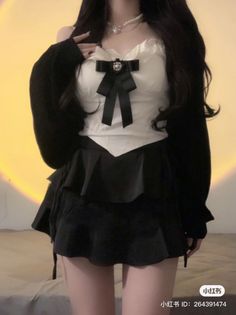 Person in a black cardigan and white top with a black skirt and pearl necklace