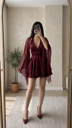 Woman in a burgundy dress and high heels taking a mirror selfie