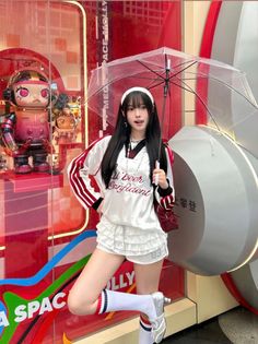Woman with long black hair holding a clear umbrella in front of a red display