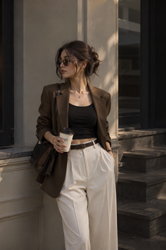Woman in a blazer and wide leg pants holding a coffee cup outdoors