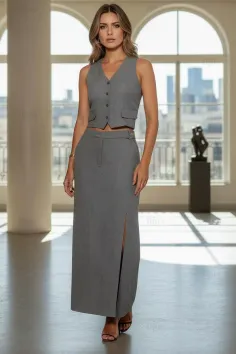 Woman in a gray vest and long skirt standing indoors with soft lighting