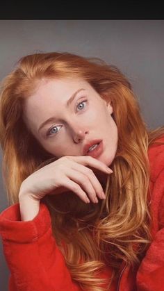 Woman with red hair and blue eyes wearing a red jacket, looking at the camera