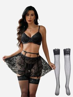 Woman in black lace lingerie and fishnet stockings posing in a studio