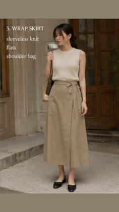 Woman in a sleeveless knit top and wrap skirt with a shoulder bag outdoors