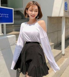 Woman with short hair wearing a white off-shoulder top and black skirt outdoors