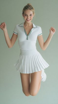 Blonde woman in a white tennis outfit jumping with a happy expression