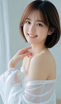 Woman with short hair wearing a white off-shoulder dress and pearl necklace