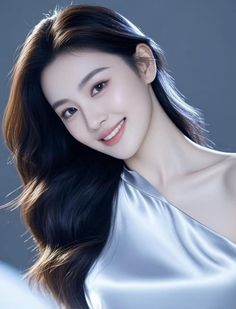 Woman with long black hair wearing a silver dress, smiling at the camera