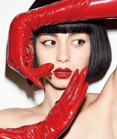 Woman with short black hair and red gloves looking to the side