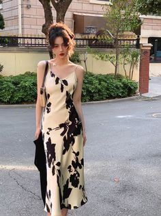 Woman in a floral slip dress standing on a street with soft lighting