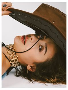 Woman wearing a cowboy hat and gold choker, looking up at the camera