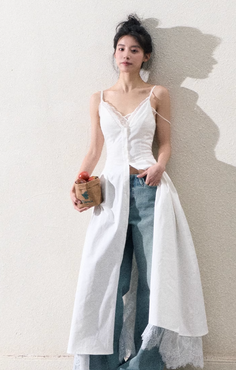Woman in a white dress over jeans holding a small bag of apples
