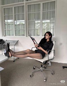 Woman in a black shirt and pantyhose with her legs up on a desk