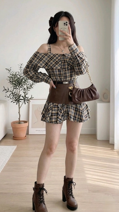 Woman in a plaid off-shoulder shirt and mini skirt holding a phone