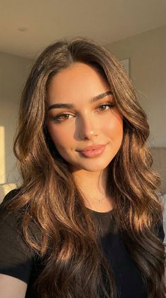 Woman with long brown hair and dimples in soft golden hour lighting