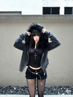 Woman in a black fur-hooded jacket, shorts, and tights outdoors