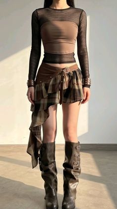 Person in a plaid skirt, mesh top, and brown boots standing indoors