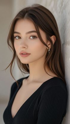 Woman with long brown hair wearing a black top and gold earrings