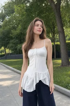 Woman with long hair wearing a white ruffle top and dark pants outdoors